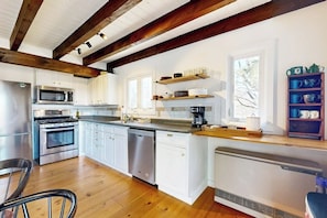 A modern kitchen with white cabinets, stainless steel appliances, and wooden beams. - Mtn-view home with large deck, wood stove, firepit, grill, streaming, W/D, & AC (Thornton)