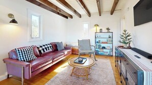 Una sala de estar con un sofá de cuero, una butaca a rayas, una mesa de centro y una estantería.