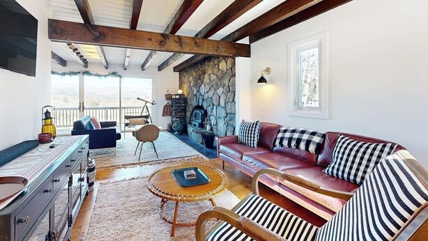 Un salón acogedor con chimenea de piedra, un sofá de cuero y una mesa de centro de madera.