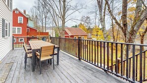 Una terraza de madera con una mesa y sillas, rodeada por una barandilla de metal negro.