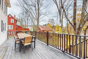A wooden deck with a table and chairs, surrounded by a black metal railing.