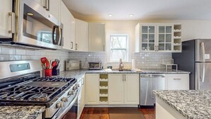 Una cocina moderna con electrodomésticos de acero inoxidable, armarios blancos y encimera de granito.