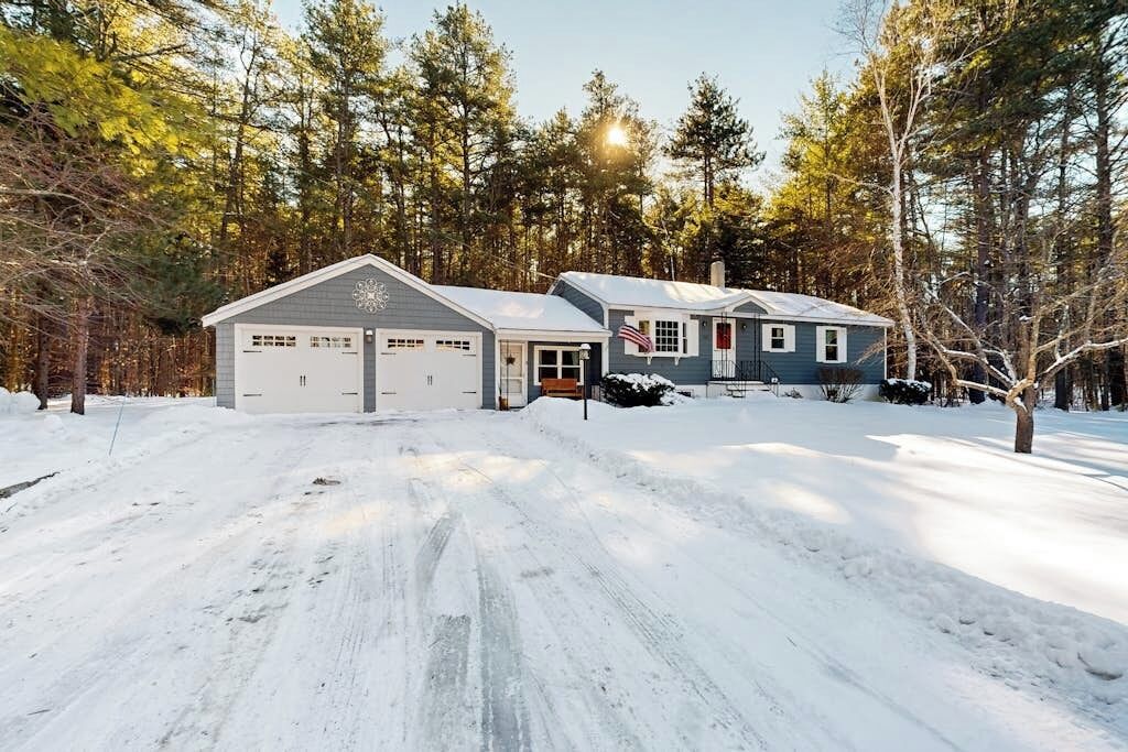 Une maison à deux étages avec un garage, une véranda et un drapeau.