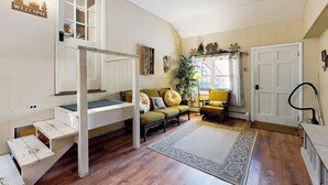 Une pièce avec un lit superposé, un canapé, un tapis et une porte.