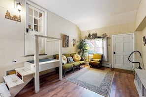 A room with a bunk bed, a sofa, a rug, and a door. - Mountain home near shops, hiking, skiing, restaurants & brewery (North Conway)