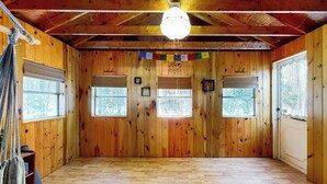 Une pièce de style cabane en bois, avec un plafond en pente, des murs en bois et une grande fenêtre.