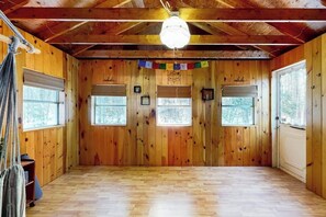 A wooden cabin room with a sloped ceiling, wooden walls, and a large window. - Mountain home near shops, hiking, skiing, restaurants & brewery (North Conway)