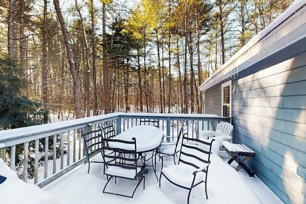 A covered outdoor patio with a table and chairs, surrounded by a railing and snow-covered ground. - Mountain home near shops, hiking, skiing, restaurants & brewery (North Conway)