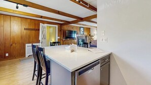 A modern kitchen with wooden beams, a central island, and built-in appliances. - Intown home w/ views, private deck & firepit; close to  Mt. Cranmore (North Conway)