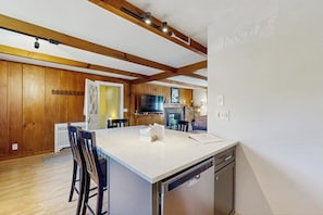 A modern kitchen with wooden beams, a central island, and built-in appliances. - Intown home w/ views, private deck & firepit; close to Mt. Cranmore (North Conway)