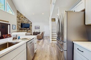 Eine moderne Küche mit Steinwand, einem großen Kühlschrank und einem Essbereich mit Blick.
