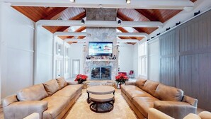 A spacious living room with leather sofas, a stone fireplace, and a television mounted above it. - Renovated Ski-in/Ski-Out Condo w/ Shared Pools, Hot Tub, Sauna & Great Location (Dover)