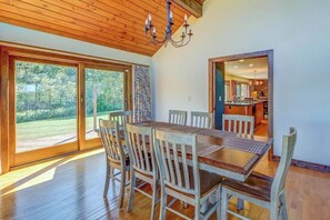 A dining area with a wooden table and chairs, large windows, and a view of the outdoors. - Secluded Luxury Home on Huge Property with Mountain Views - Near Slopes (Brownsville)