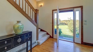 A staircase leading to a second floor, a door with a glass panel, and a vase on a console table.
