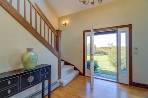 A staircase leading to a second floor, a door with a glass panel, and a vase on a console table. - Secluded Luxury Home on Huge Property with Mountain Views - Near Slopes (Brownsville)