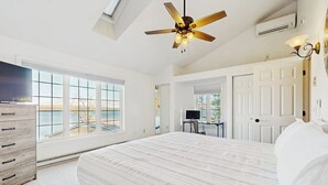 Un dormitorio con una cama grande, ventilador de techo, televisión y vistas al exterior.