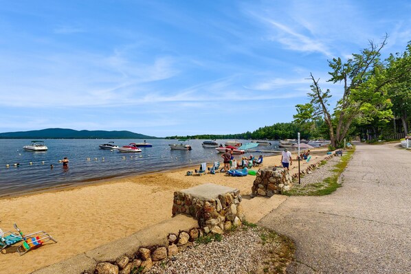 A beach with boats, a stone wall, and a clear sky.