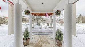 A covered outdoor area with columns, potted Christmas trees, and festive decorations. - Mountainside condo w/ pool & rec room; walk to lifts & town (Lincoln)