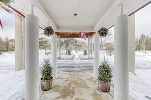 Ein überdachter Außenbereich mit Säulen, Topf-Weihnachtsbäumen und festlicher Dekoration.