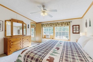 Ein Schlafzimmer mit einem großen Bett, einem Holzschrank, einem Deckenventilator und einem Fenster mit Vorhängen.