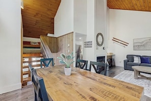 Ein großzügiger Wohnbereich mit einem Holzesstisch, Stühlen, einer Couch und einer Treppe, die in eine obere Etage führt.
