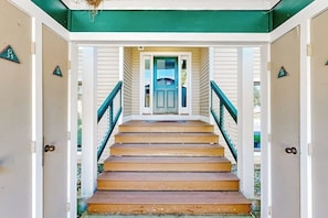 A staircase leading to a door with a green frame, flanked by white walls and numbered doors. - Ski-in/ski-out condo w/ deck, wood-burning fireplace, wifi, community amenities (Dover)