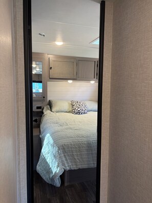 Ein Schlafzimmer mit Bett, Kissen, Nachttisch, Kommode und Fenster.