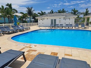 A swimming pool with lounge chairs, a small building, and palm trees. - Costa Azul Bimini Bay (Bailey Town)