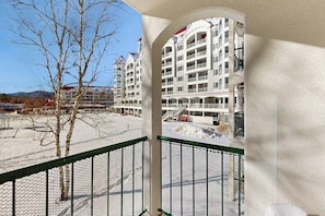 A hotel with multiple floors, balconies, and a view of a snowy landscape. - Mountainside Condo: walk to ski lift & town w/ pool & rec room (Lincoln)