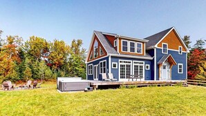Une maison à deux étages dotée d’une grande terrasse, d’un patio couvert et d’une cour gazonnée.