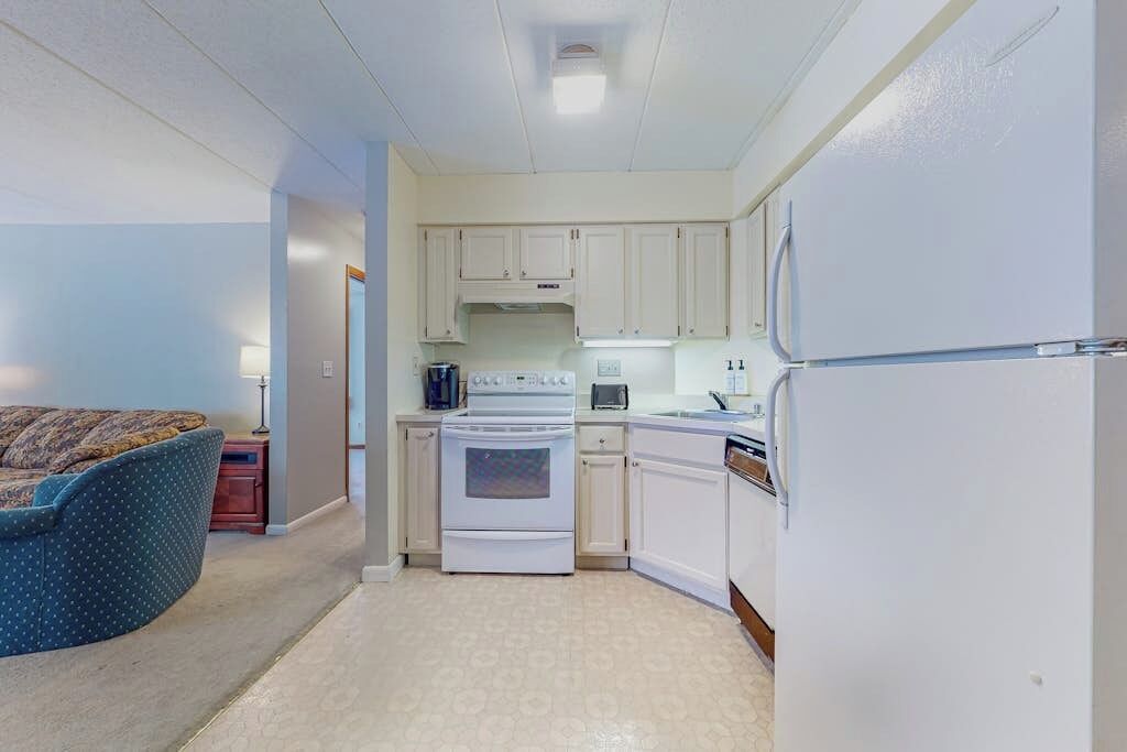 A compact kitchen with white cabinets, a stove, and a refrigerator.
