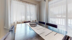 Ein Zimmer mit Esstisch, dekorativem Korb und transparenten Vorhängen.