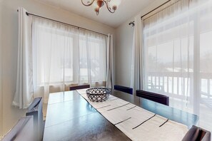 Ein Zimmer mit Esstisch, dekorativem Korb und transparenten Vorhängen.