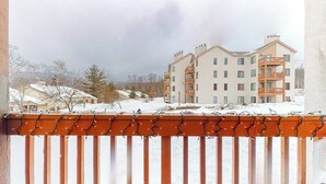 Ein mehrstöckiges Gebäude mit Balkonen, einer verschneiten Landschaft und einem bewölkten Himmel.