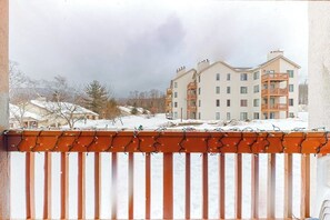 Ein mehrstöckiges Gebäude mit Balkonen, einer verschneiten Landschaft und einem bewölkten Himmel.