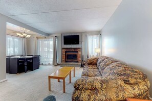 Ein Wohnzimmer mit Sofa, Fernseher, Kamin und Schreibtisch mit Stuhl.