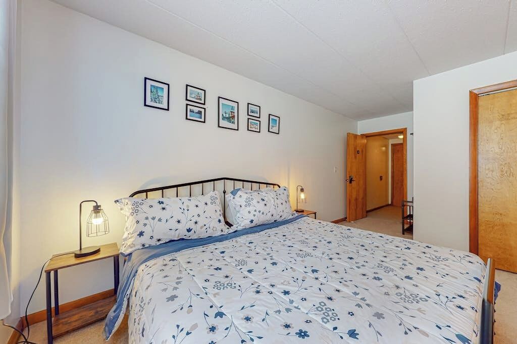 A bedroom with a bed, bedside tables, and framed pictures on the wall.