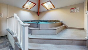 En trappe med fritstående jacuzzi, ovenlysvinduer og et advarselsskilte.