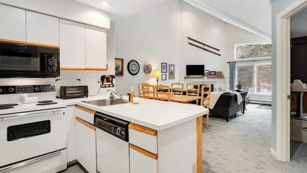 A modern kitchen with white cabinetry, a microwave, a toaster, and a dishwasher. - Slopeside condo with nearby skiing, balcony, fireplace, & washer/dryer (Dover)
