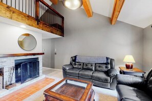 Ein Wohnzimmer mit Kamin, Ledersofa, Couchtisch und einer Treppe.
