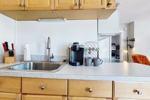 Eine Küche mit Holzausstattung, einem Edelstahl-Spülbecken, einer Kaffeemaschine und einem Becherhalter.