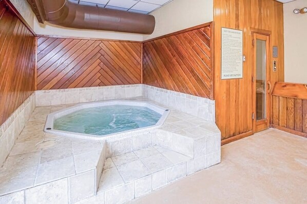 A hot tub in a corner with wooden paneling and a sign on the wall.