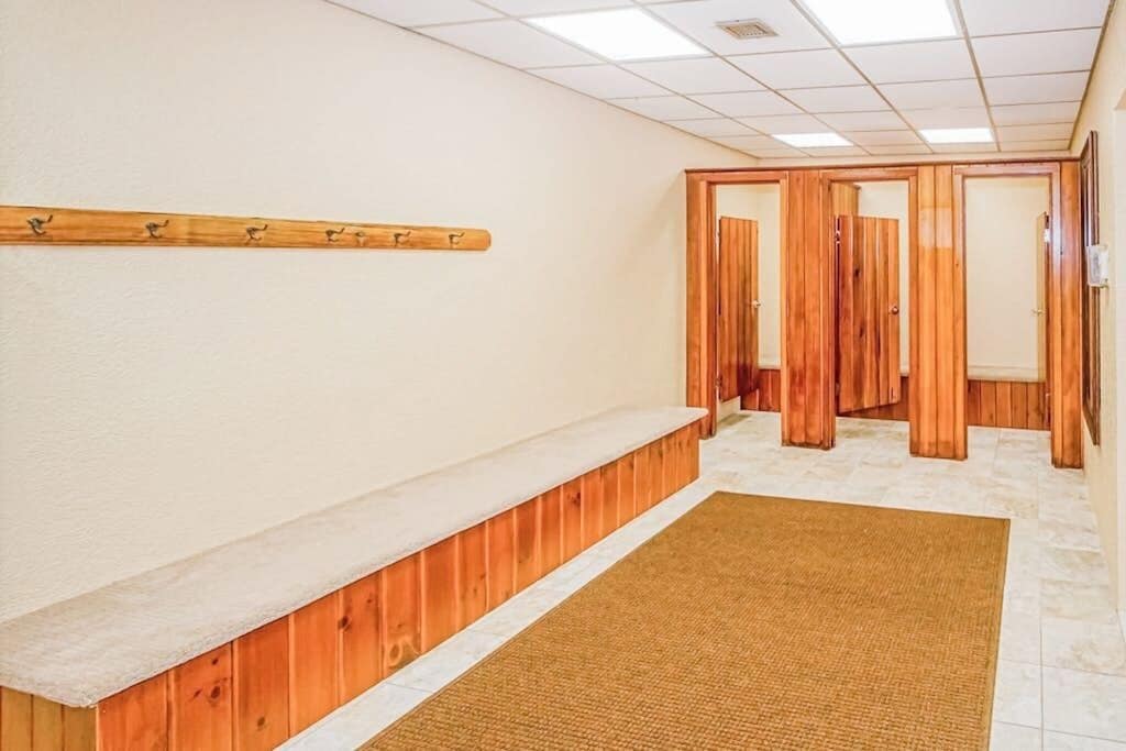 A hallway with a wooden bench, a wall-mounted coat rack, and a door leading to another room.