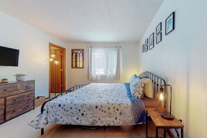 A bedroom with a bed, bedside table, lamp, dresser, and a window with curtains. - Cozy retreat near slopes (Dover)