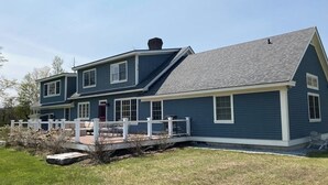 A two-story house with a covered patio, a fenced yard, and a chimney.