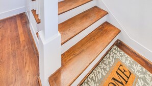 A staircase with wooden steps and white railings, leading to a landing with a doormat. - Newly Furnished Cozy 2B~Mins to Medical center&NRG~Near Rice U~ Downtown Houston (Houston)