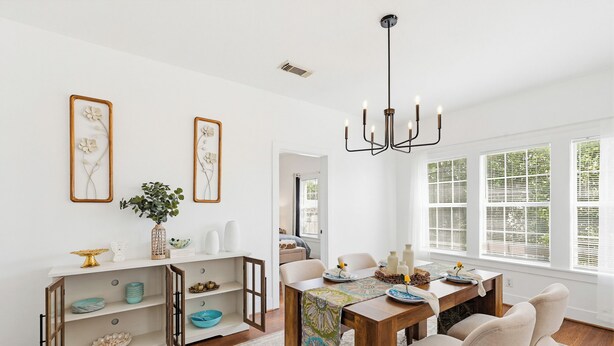 A dining area with a wooden table, chairs, a chandelier, and artwork on the walls. - Newly Furnished Cozy 2B~Mins to Medical center&NRG~Near Rice U~ Downtown Houston (Houston)