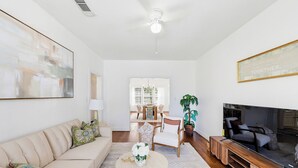 A living room with a sofa, coffee table, TV, and a dining area in the background. - Newly Furnished Cozy 2B~Mins to Medical center&NRG~Near Rice U~ Downtown Houston (Houston)