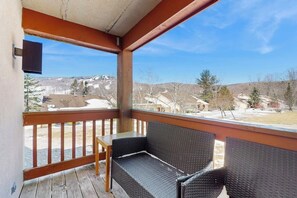 A covered porch with wicker furniture and a view of a snowy landscape. - Comfortable condo with fireplace, pool, and sauna access - near slopes (Dover)