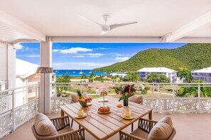 Ein Balkon mit Holztisch, Stühlen und Blick auf das Meer und die Gebäude.